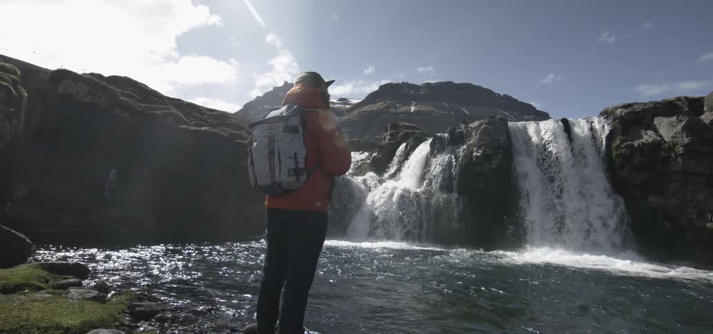 A hiker stops to watch large waterfalls