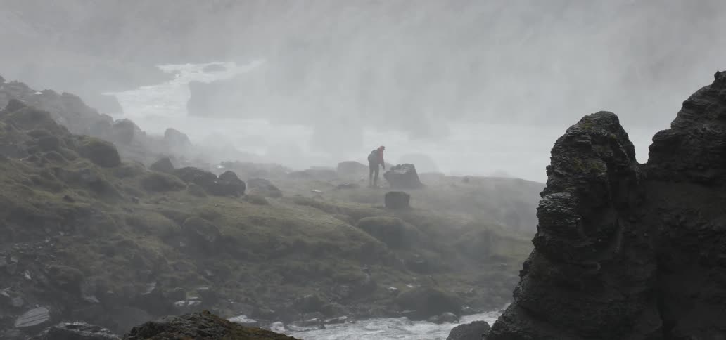 Lone hiker standing atop a rock on a very foggy and cloudy day