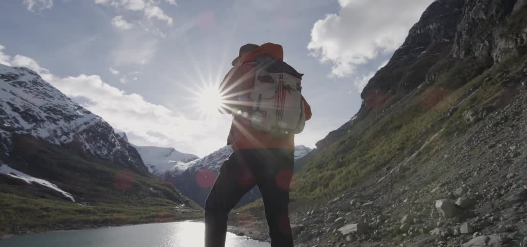 Hikers standing atop some rocks looking down towards a river flowing between mountains