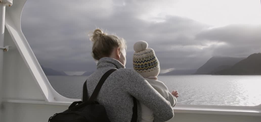 A woman holds her baby next to the side of a boat