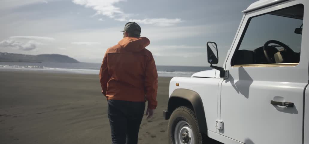 Man and woman exit a vehicle parked on a sandy beach