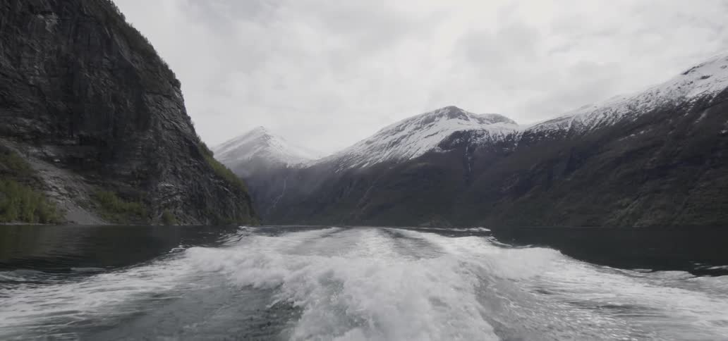 Waves being formed from a boat moving rapidly through water as seen from the rear of the boat on a cloudy day