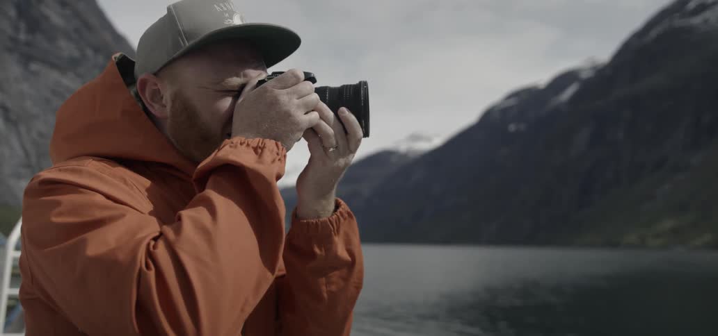 A man is taking a photograph by a river