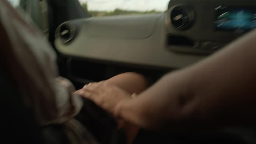 Driver reaches across to touch the passenger during a trip on a cloudy day