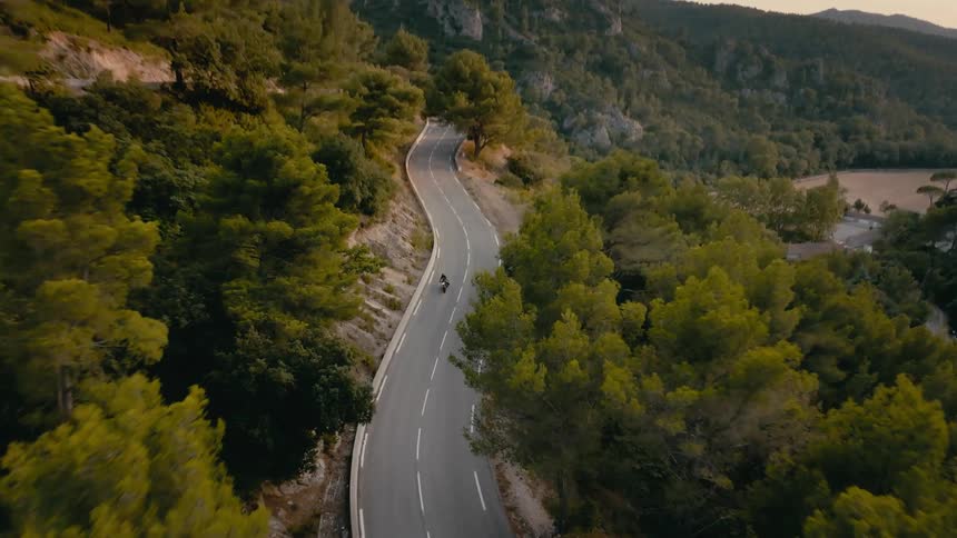 A person rides a motorcycle down a road in a rural area