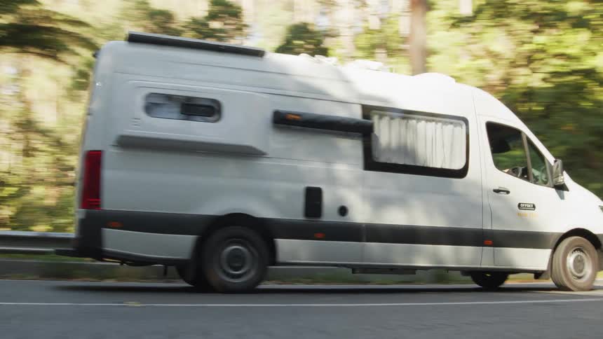 A white van driving on an asphalt street and making a turn