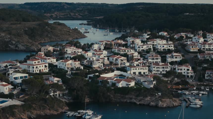 A town with several white houses on a hill facing the sea