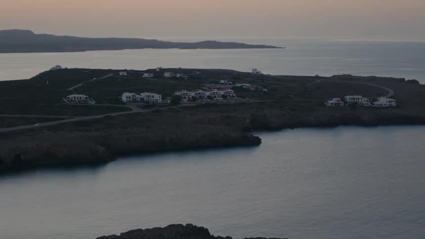 Aerial of large houses built on an ocean promontory at dusk