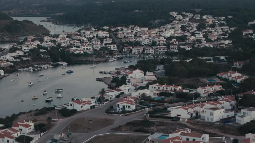 An aerial view of coastal cityscape nestled between a bay and rolling hills