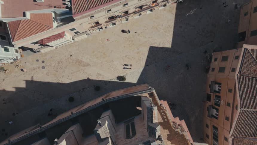 An aerial view of some people walking down a street with several buildings on the sides