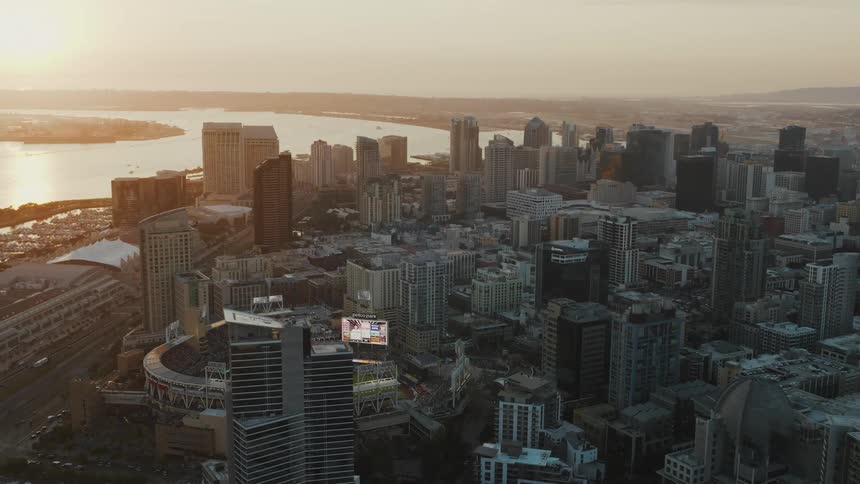 A aerial view of a bustling San Diego skyline with a baseball stadium in the foreground