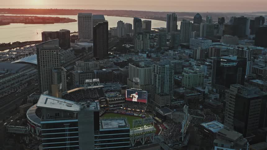 Aerial of a baseball game in a stadium in a metropolis at dusk