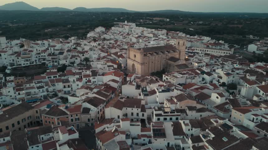 An aerial view of a city with white houses and a large monastery in the center