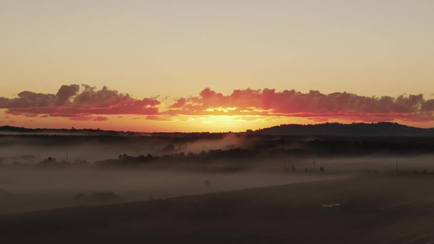A haze hangs over wide open plains in front of a mountain