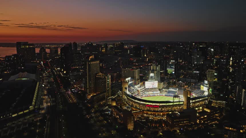The bright lights of Petco Park light up the downtown San Diego skyline bathed in pink sunset light