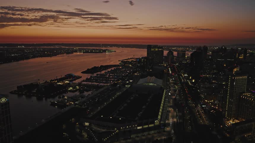 Aerial shot of downtown San Diego's city lights and waterfront bathed in pink and orange light