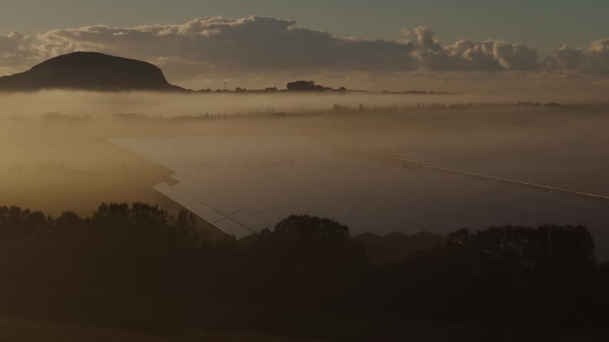 A solar panel farm with thick fog above them on an early morning