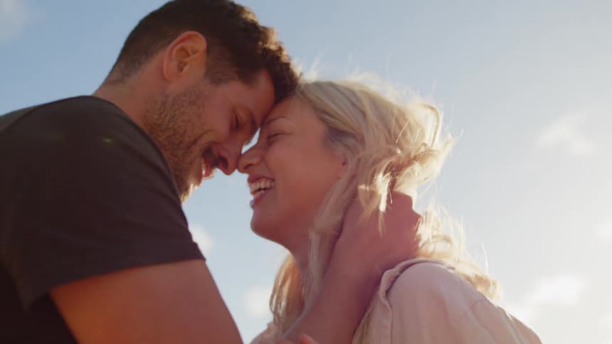 A man holds his girlfriends face close to his as they both laugh together