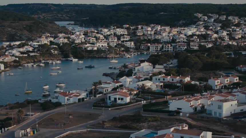 A coastal cityscape with white houses and a harbor filled with boats