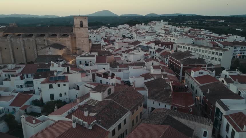 An aerial view of a town with many small white houses with a monastery in the left side