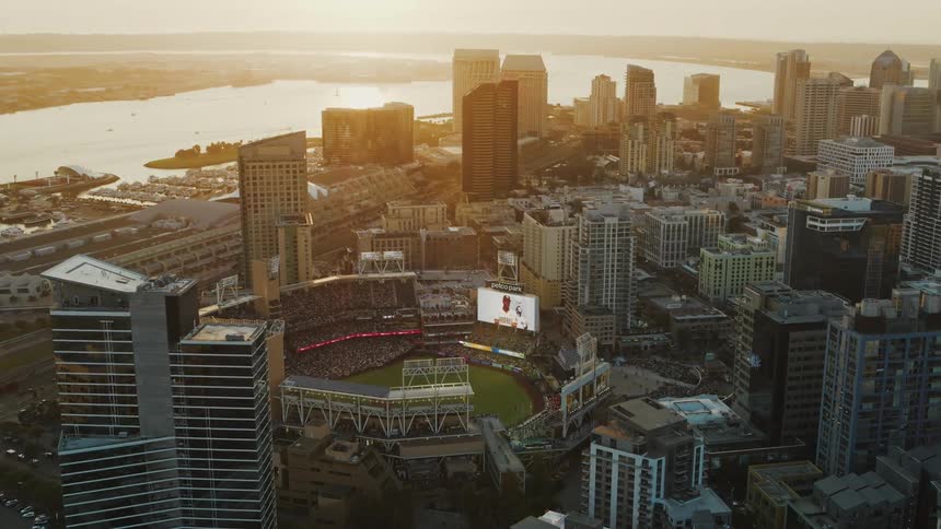 Fans fill a sports stadium located a block from the waterfront in a riverside city at sunset