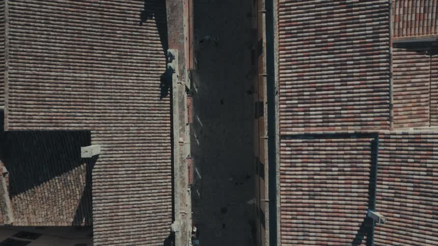 An aerial view showed a concrete street with some houses on the side with tiled roofs