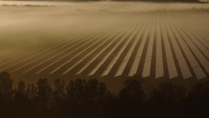 A solar panel farm pointing to the sky and the weather is foggy