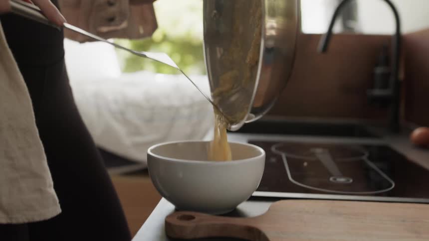 Person scrapes food into a bowl after cooking in a recreational vehicle while camping