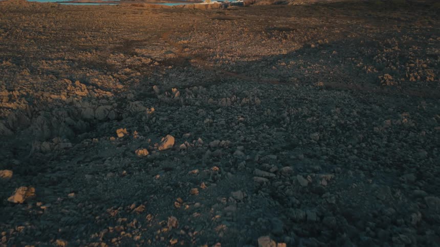 Aerial of rocky land near an ocean coast at dusk