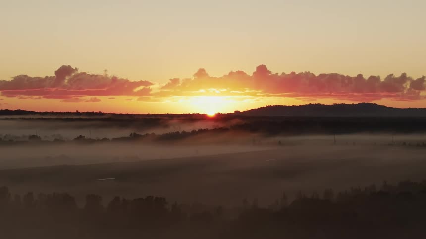 The sun is rising on the fog filled horizon