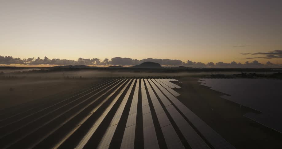 Solar panels fill a large plain near a mountain range
