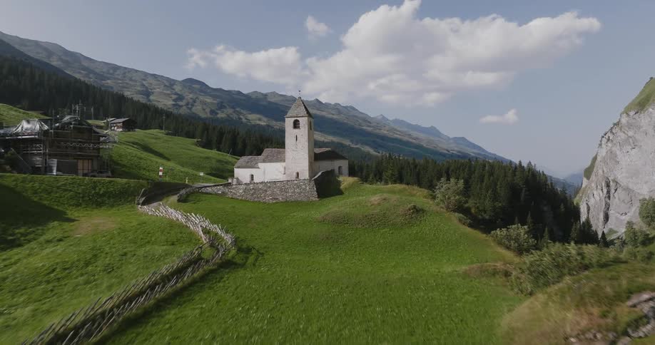 Church sits between the lip of a canyon and a road passing through a small town before entering the forest on a cloudy day
