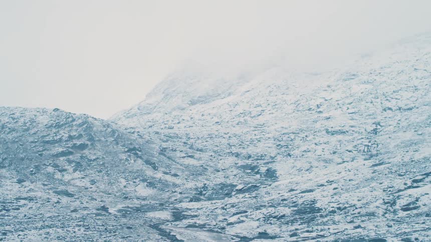 Fog shrouds the top of a snow covered mountain