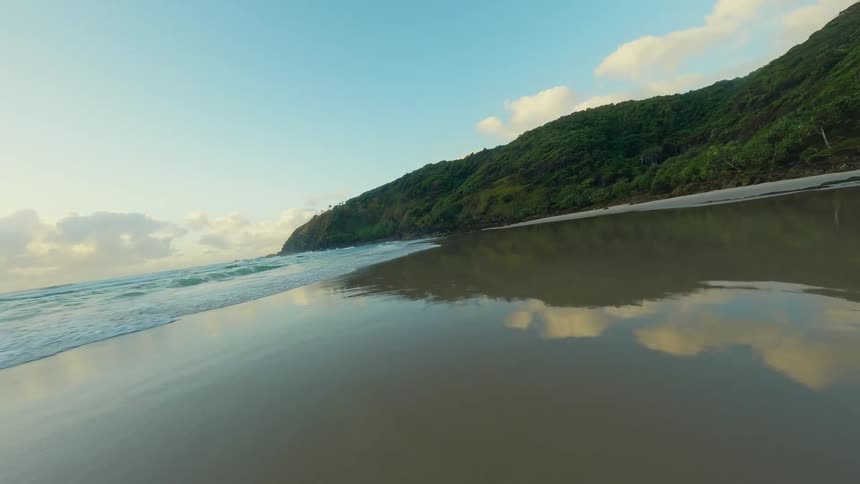 A beach in a lagoon surrounded by forest covered mountains