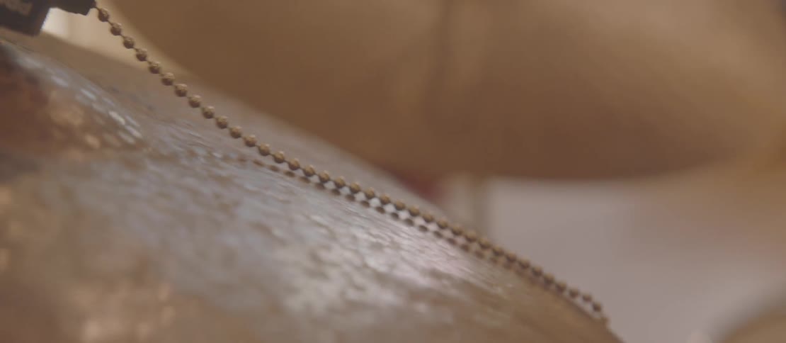 Closeup of a drumstick striking cymbals with sizzlers or rattlers
