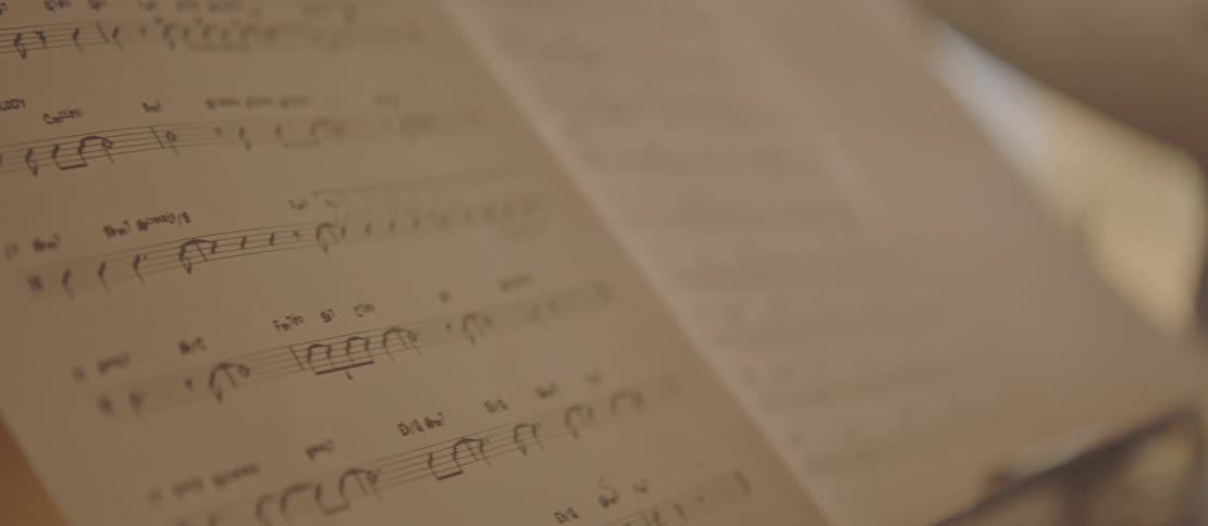 Sheet music sits near a black man playing the drums