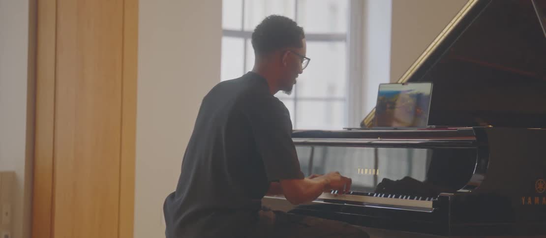 Seated man wearing glasses playing piano