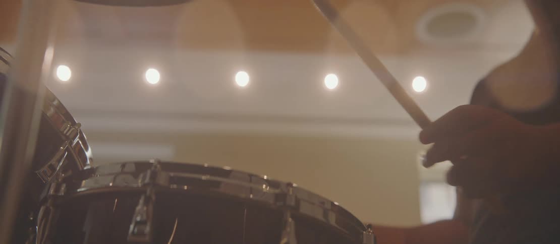 Hands of a person playing drums in an indoor setting