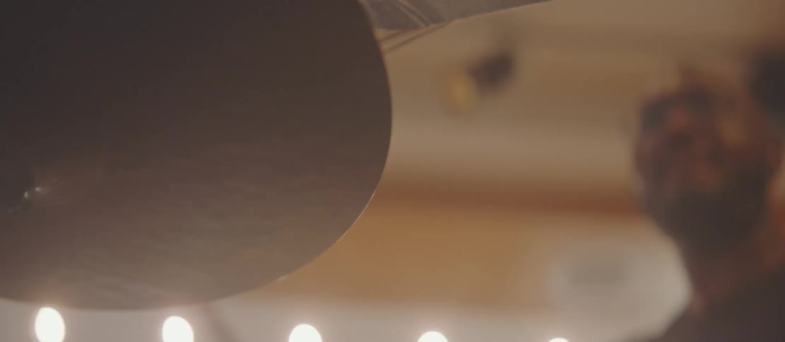 Male musician plays the drums in a brightly lit room