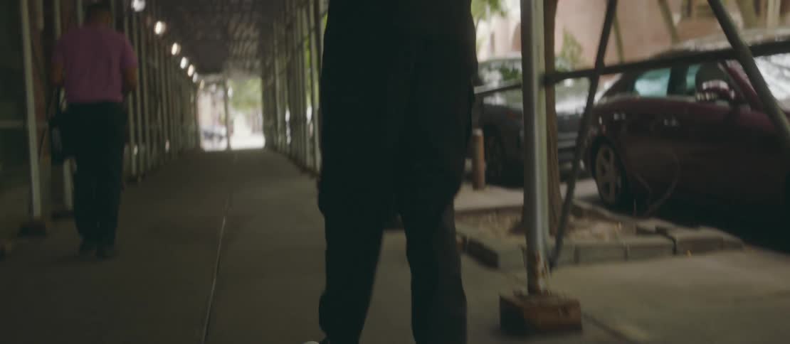 Man with a handbag walking on a city sidewalk