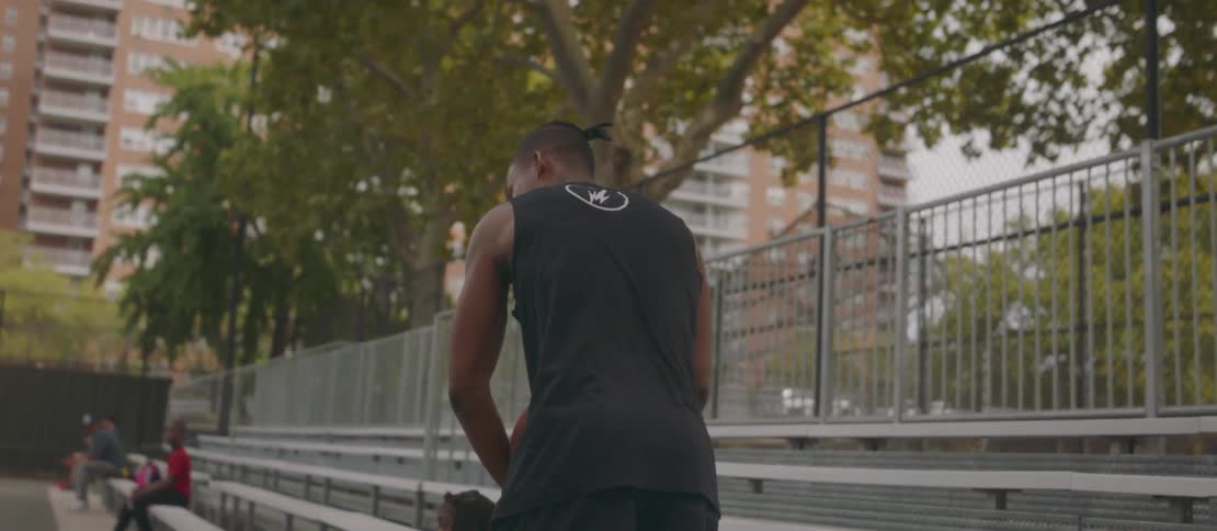Friends playing basketball on an outdoor court with a chainlink fence and trees in the background