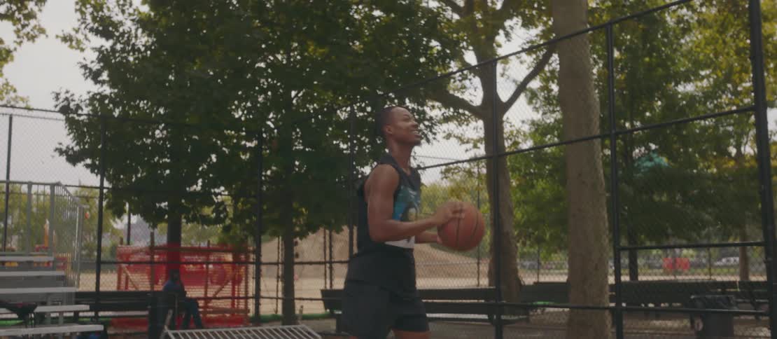 Two young men playing basketball in a city park with one of them shooting the ball at the hoop and failing