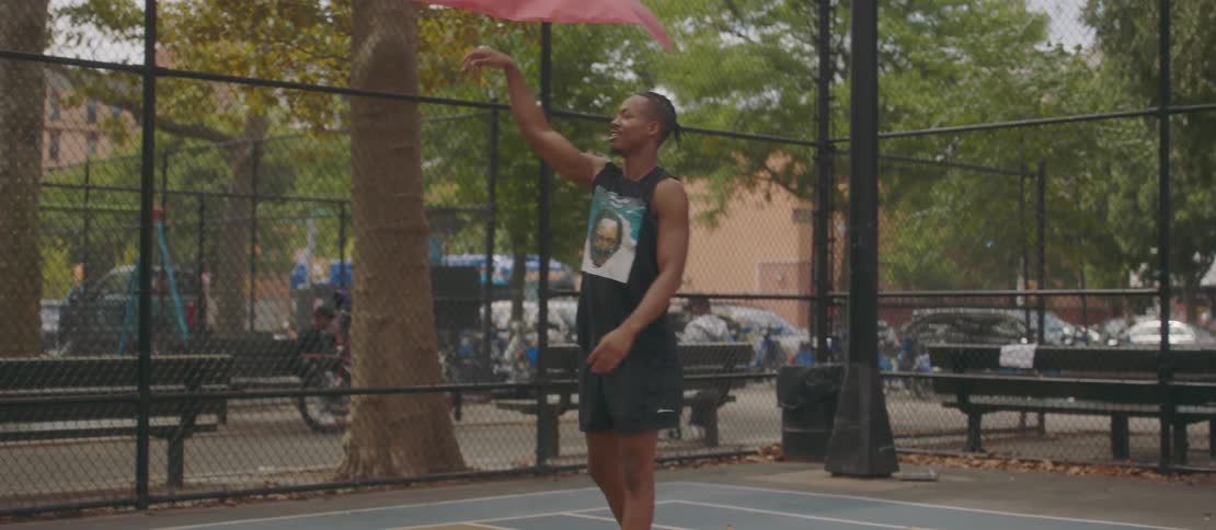 Young man on an outdoor court shooting a basketball into the hoop