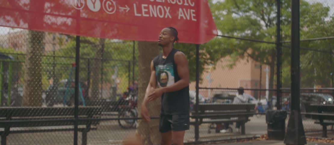 Friends playing basketball on an outdoor court with a chainlink fence and trees in the background
