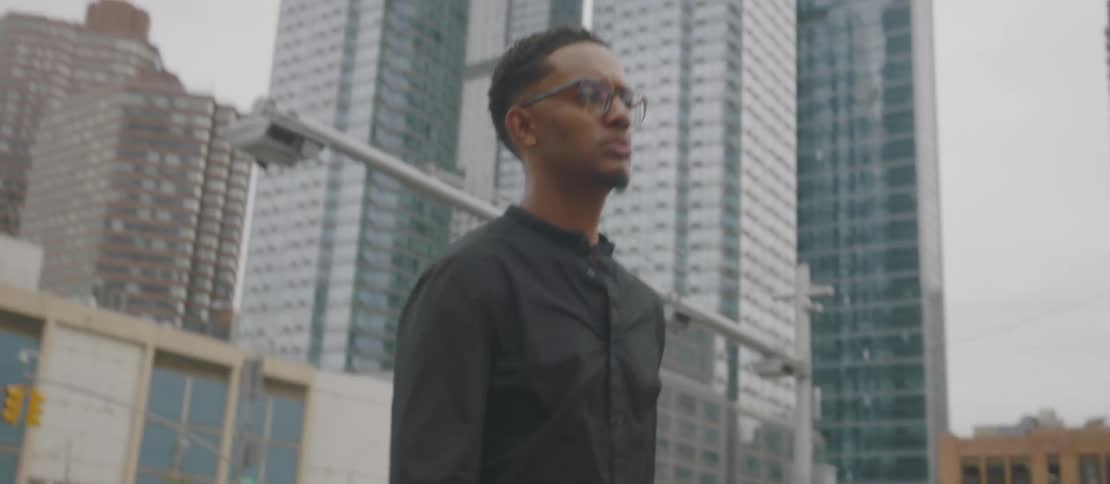 Person walking on an urban street lined with buildings listening to music