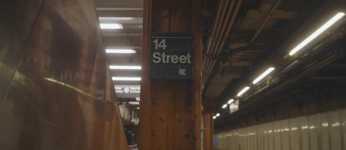 Passengers wait on the station platform near 14 street