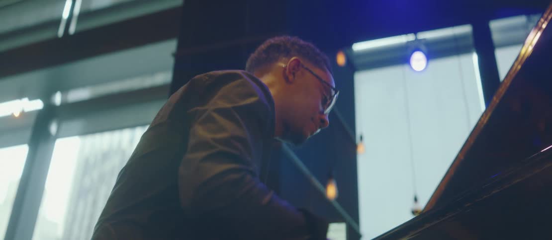 A black male smiles and has fun playing the piano in a room