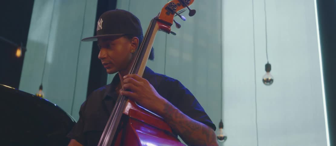 A young man with a cap is playing a cello violin
