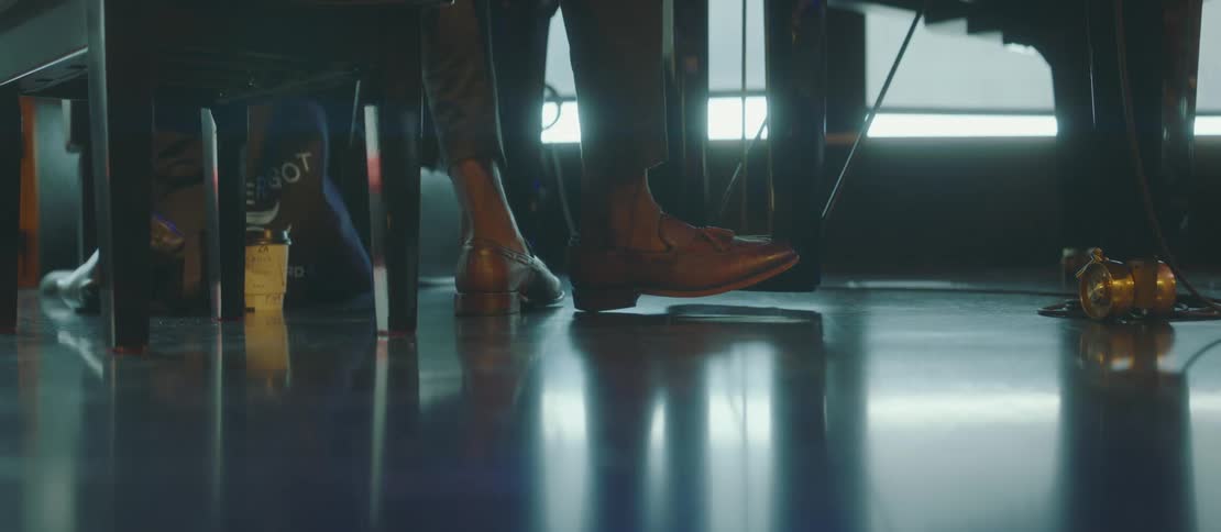 Feet of a musician with shoes sitting playing the ground next to a piano