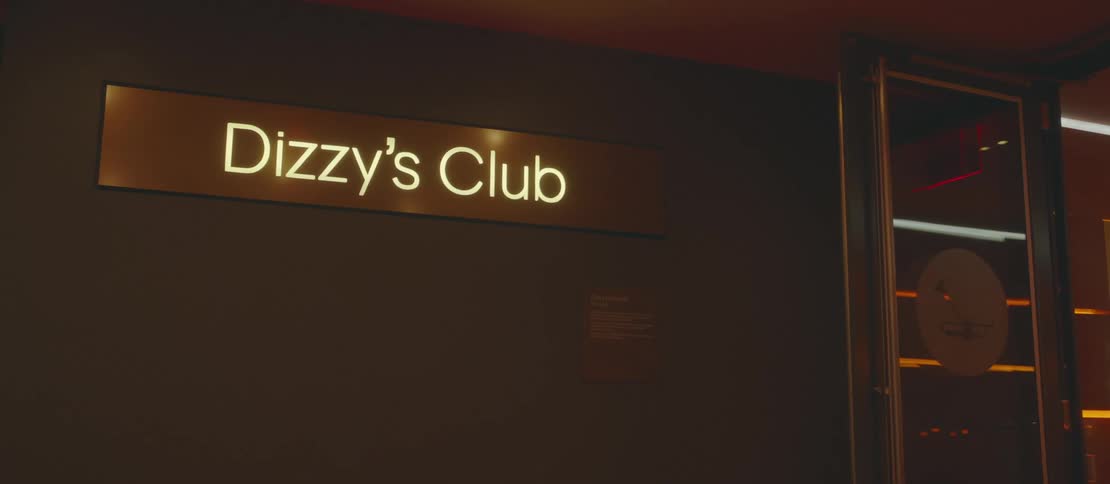 A yellow illuminated sign on the dark wall of a club